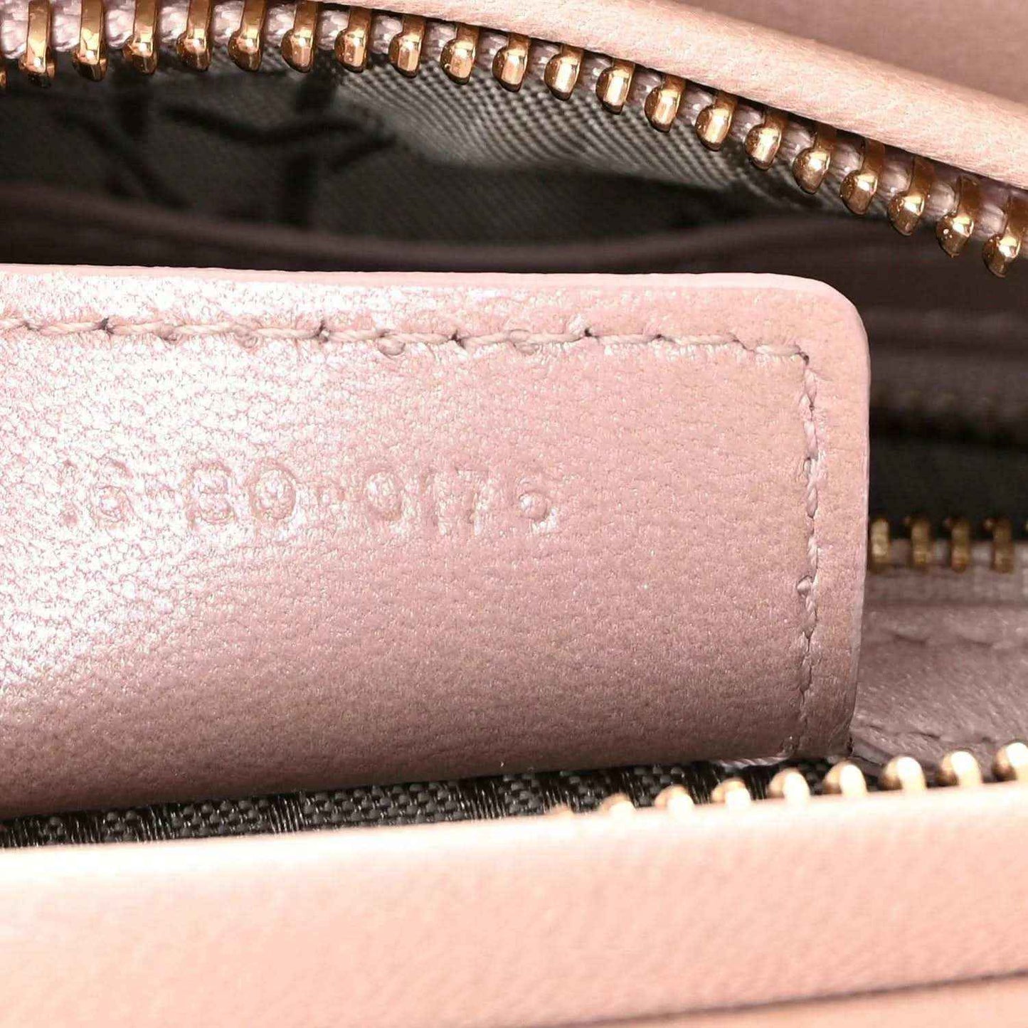 Close-up of light pink leather trim with gold zipper and embossed lettering
