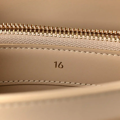 Gold zipper teeth and beige lining with stitched seam inside a small bag