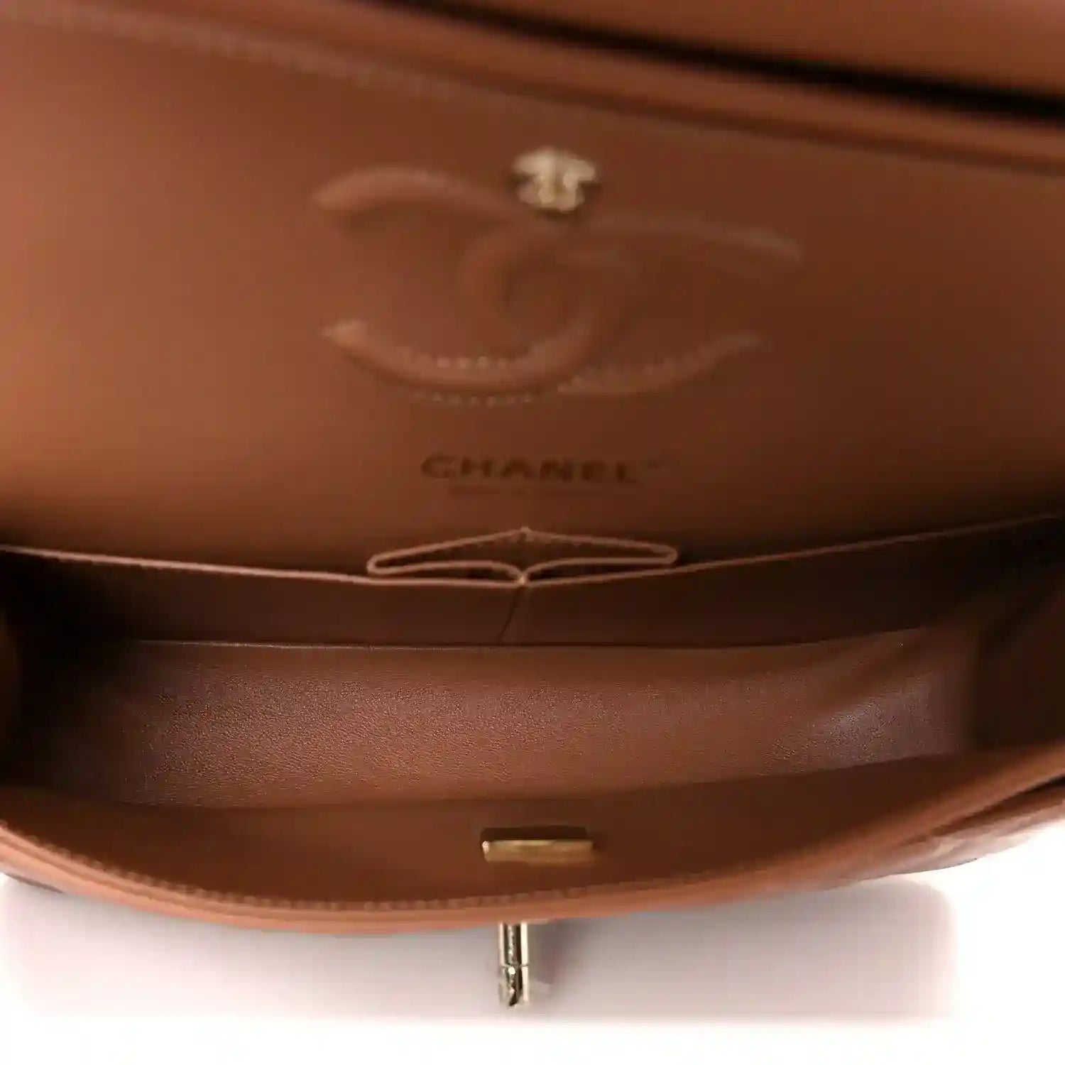 Interior view of brown leather bag showing CHANEL logo stamp and zipper area.