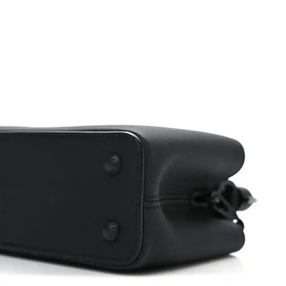 Mini black leather handbag side panel with corner hardware and strap ring.