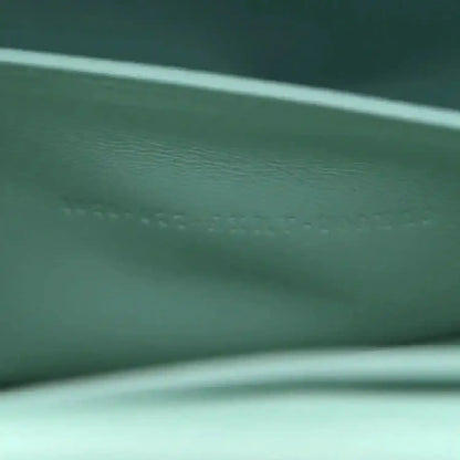 Blue satin baguette bag close-up of embossed text and leather texture