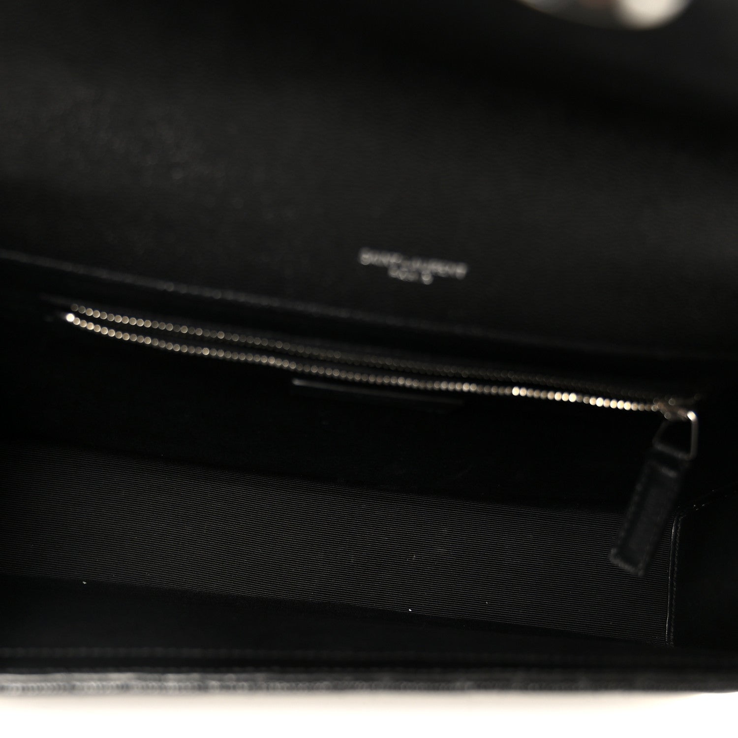 Black satchel interior with zipper track and zipper pull visible at opening