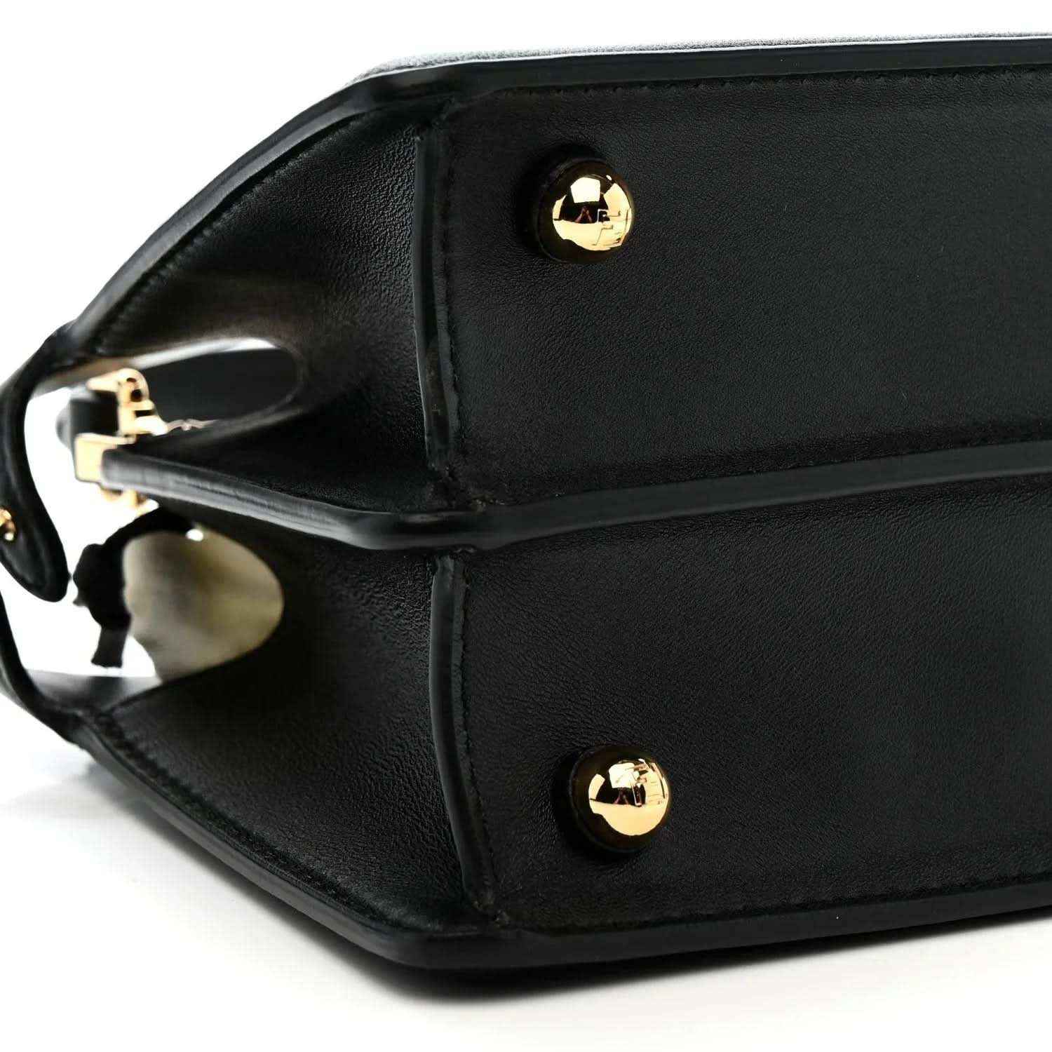 Black leather satchel corner with gold-toned circular studs and strap ring