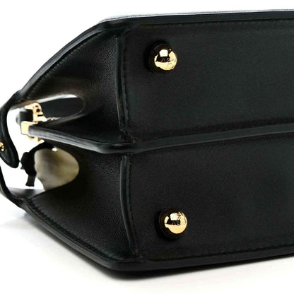 Black leather satchel corner with gold-toned circular studs and strap ring