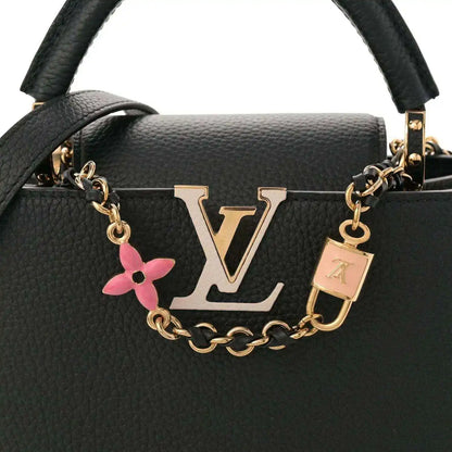 Black leather handbag front with gold LV logo, chain strap, and pink enamel flower charm