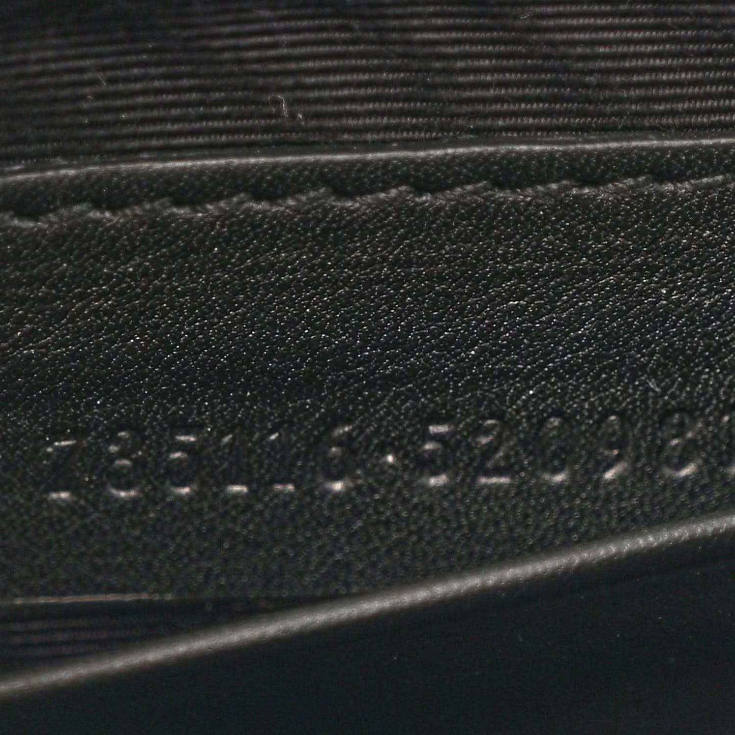 Close-up of stamped details on black mini bag strap area