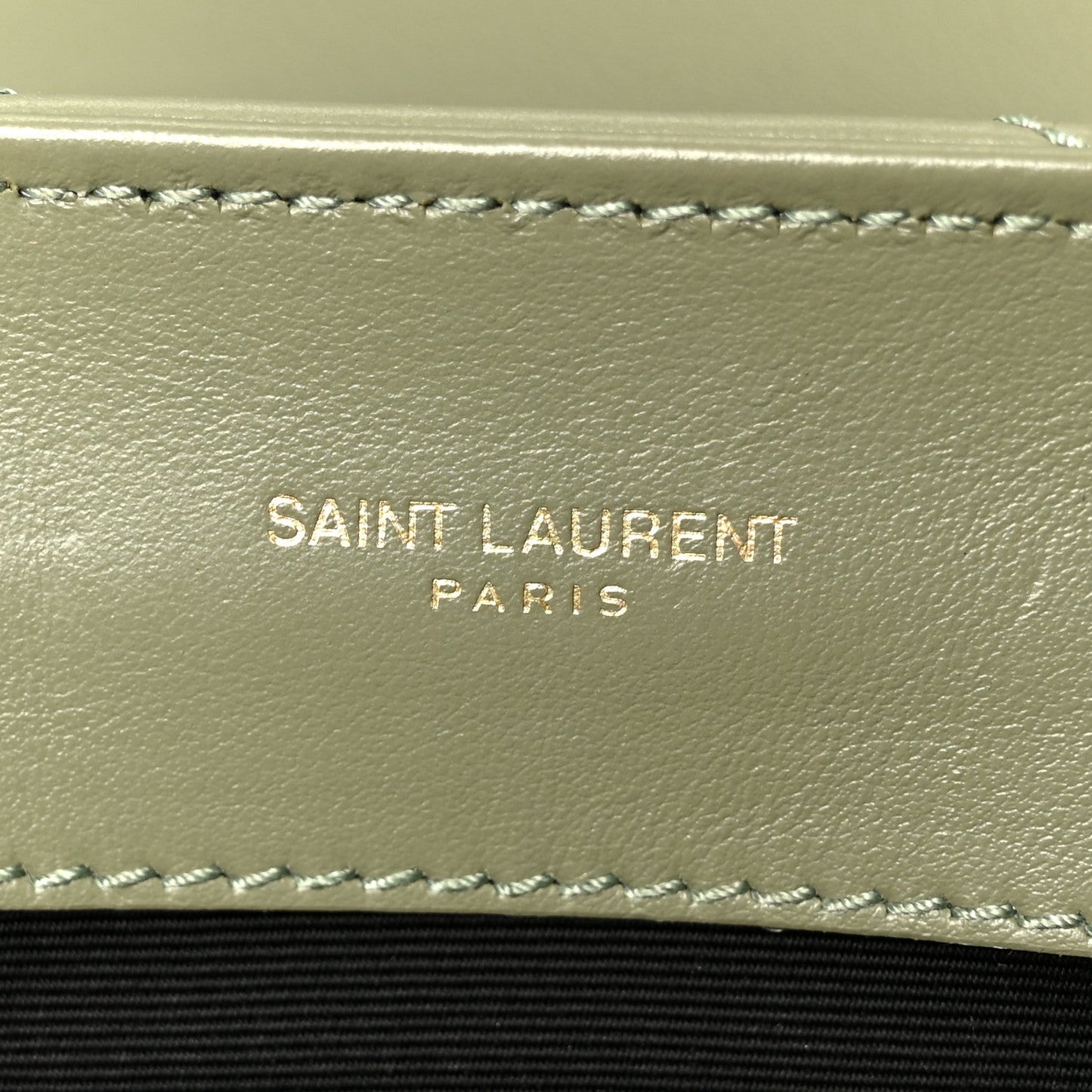 Light sage leather satchel interior wall with stitched trim and “SAINT LAURENT PARIS” text