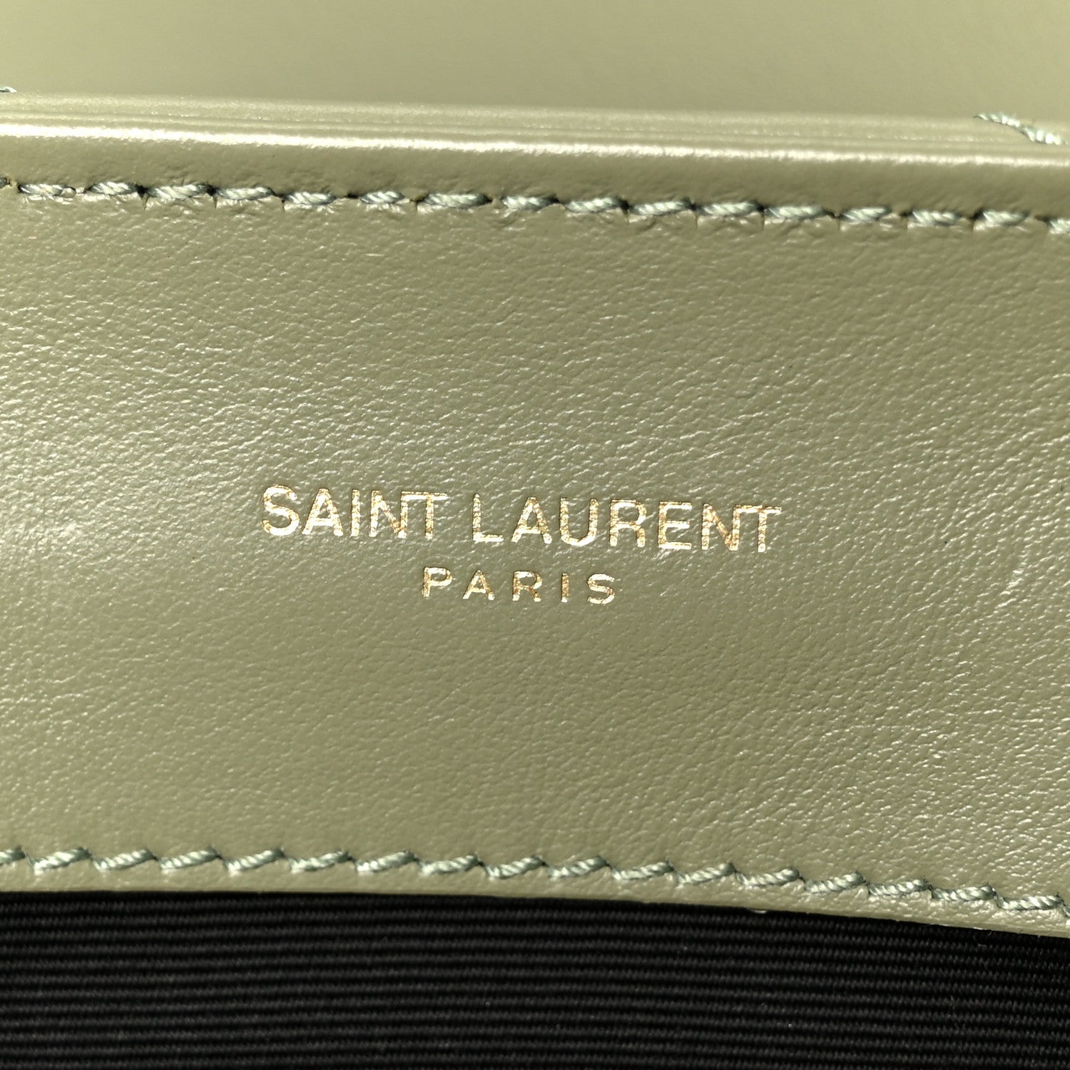 Light sage leather satchel interior wall with stitched trim and “SAINT LAURENT PARIS” text