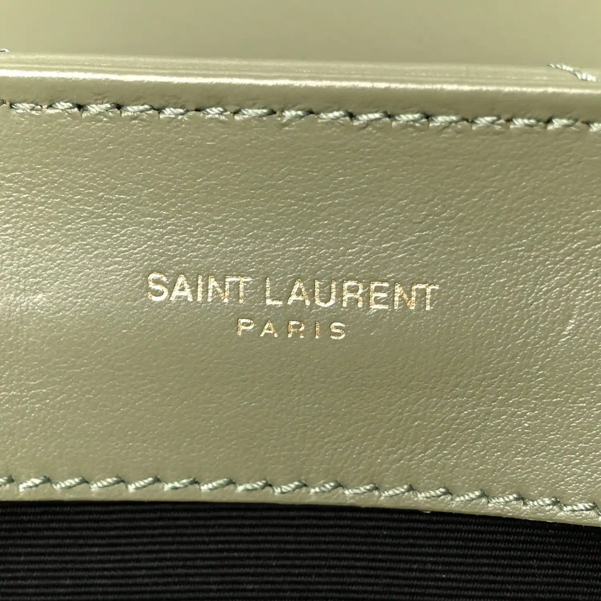 Light sage leather satchel interior wall with stitched trim and “SAINT LAURENT PARIS” text