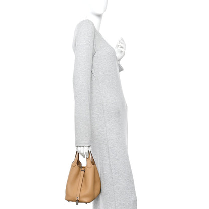 Tan leather bucket bag worn on shoulder with top handles