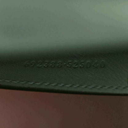 Green tote bag underside with embossed serial-style numbers and stitched seam