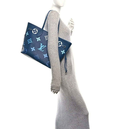 Blue monogram tote bag with matching pouch hanging from side straps
