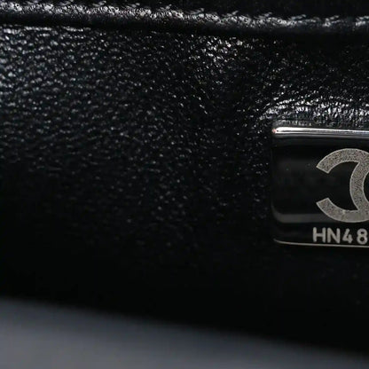 Black satin flap close-up with Chanel emblem hardware and HN48 stamp