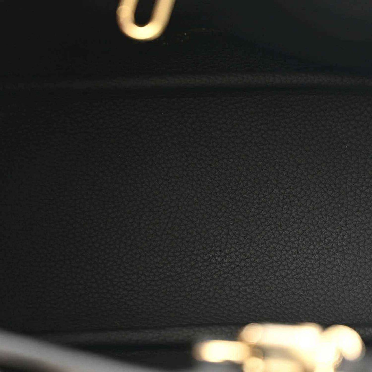 Black leather panel detail with textured grain and small gold hardware at top edge