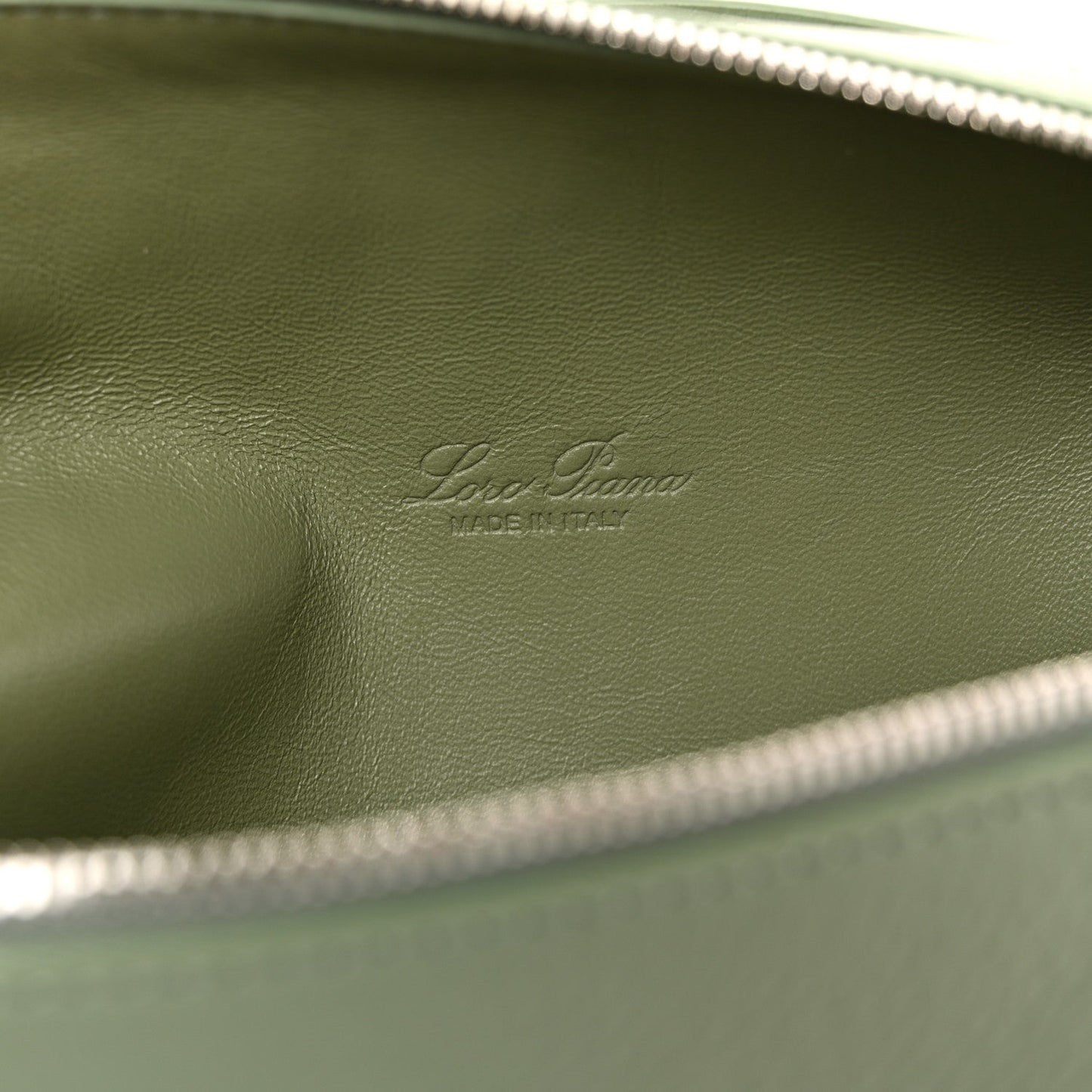Embossed Loro Piana mark on sage green leather lining, close-up