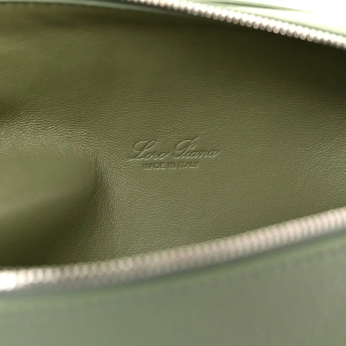 Embossed Loro Piana mark on sage green leather lining, close-up