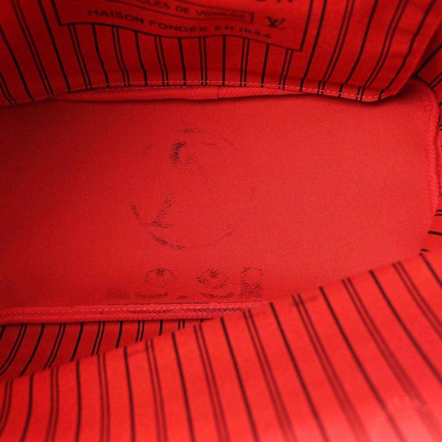 Red fabric lining with embossed monogram pattern inside the bag