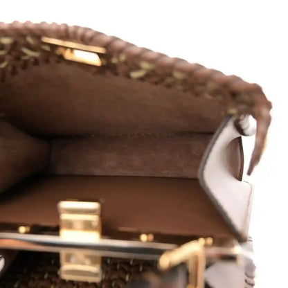 Brown leather interior and woven edge with front hardware visible on satchel