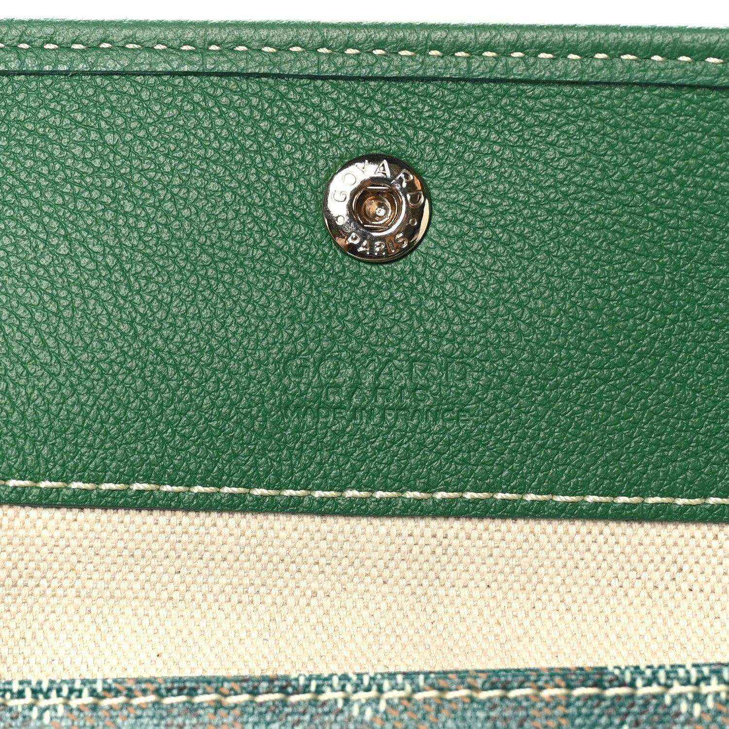 Green leather tab detail with circular metal snap on the tote bag