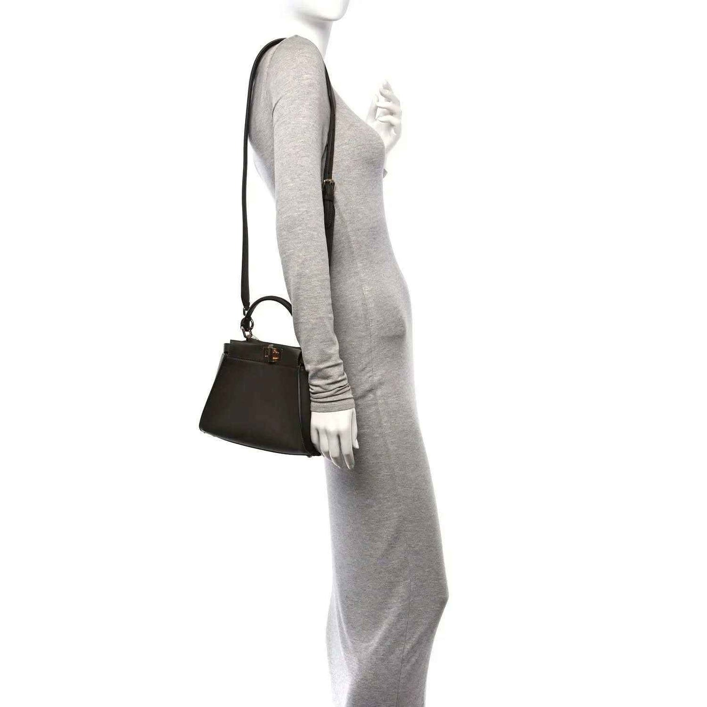 Mini satchel in dark brown leather with shoulder strap; worn crossbody style.