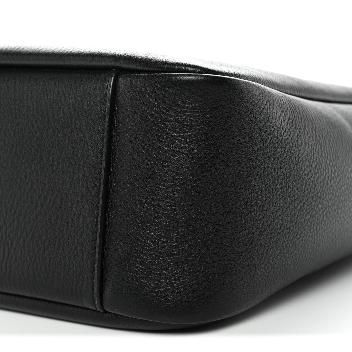 Black calfskin hobo bag corner with visible panel stitching and smooth surface.