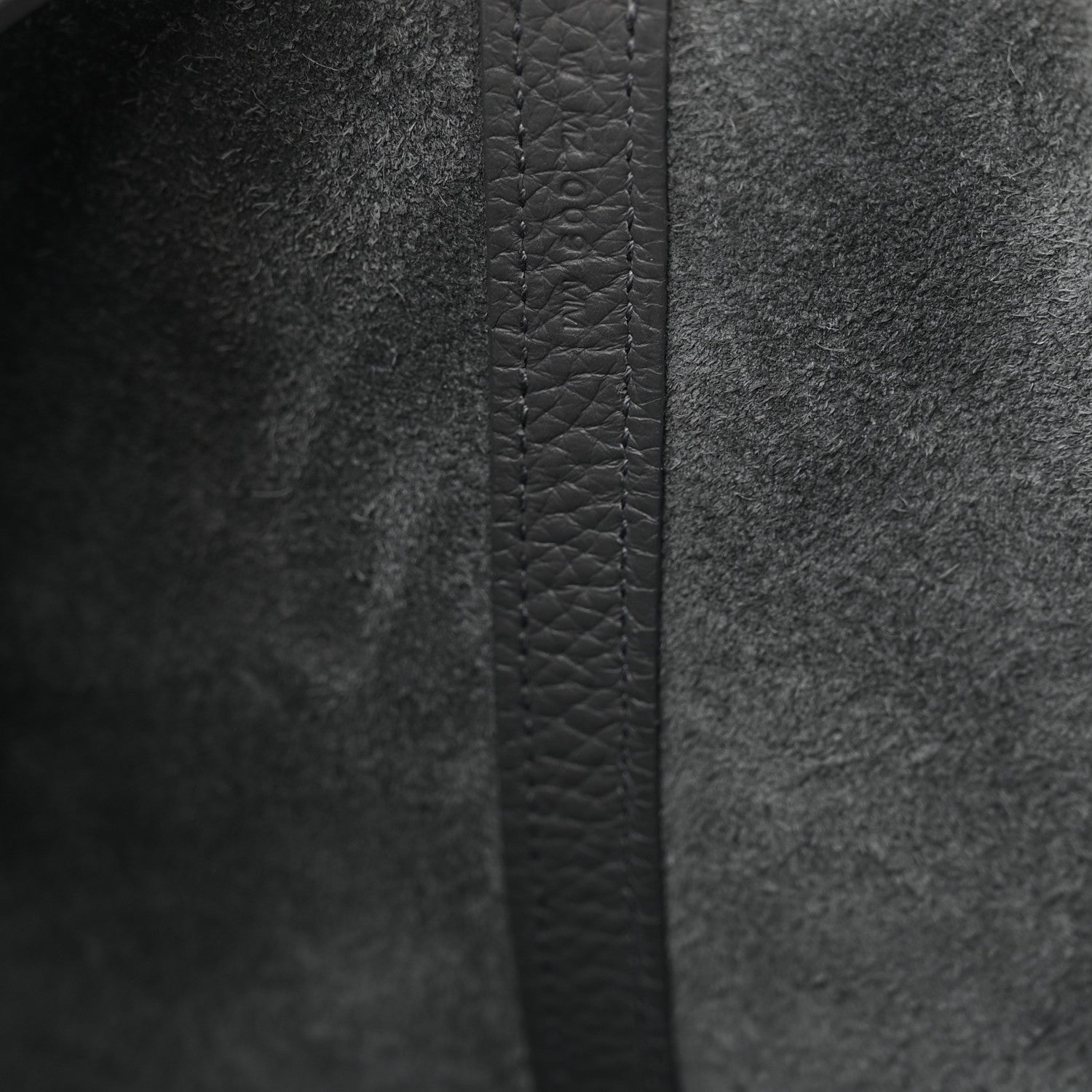Close-up of dark gray leather side panel with stitched seam and textured grain