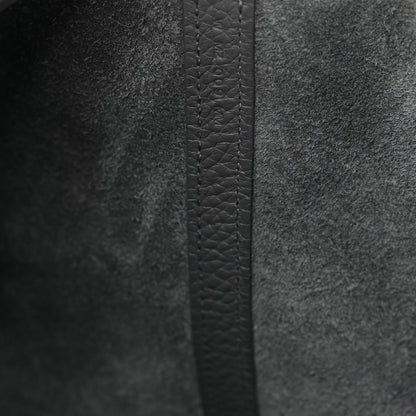 Close-up of dark gray leather side panel with stitched seam and textured grain