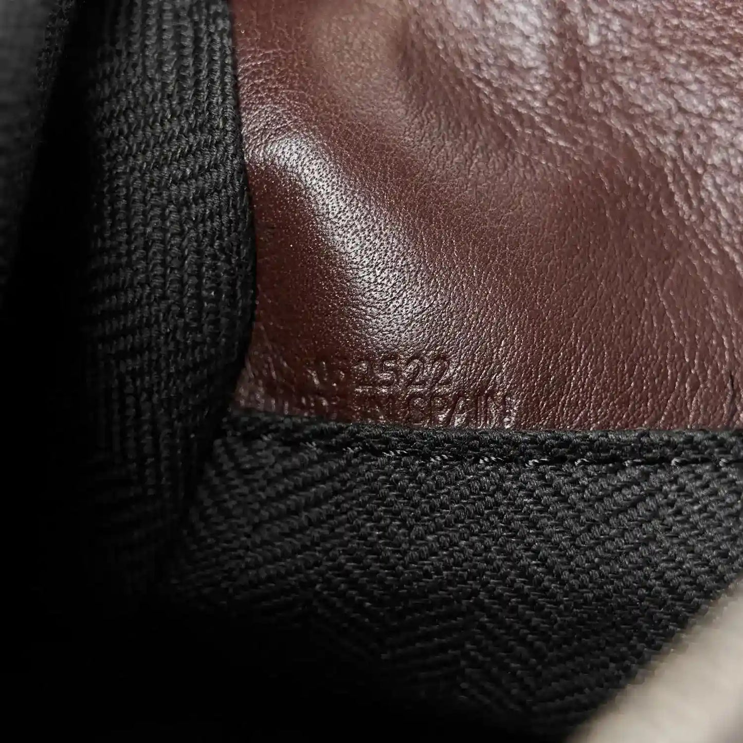 Close-up of leather panel and fabric strap attachment on small biker bag, dark brown