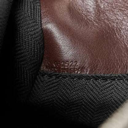 Close-up of leather panel and fabric strap attachment on small biker bag, dark brown