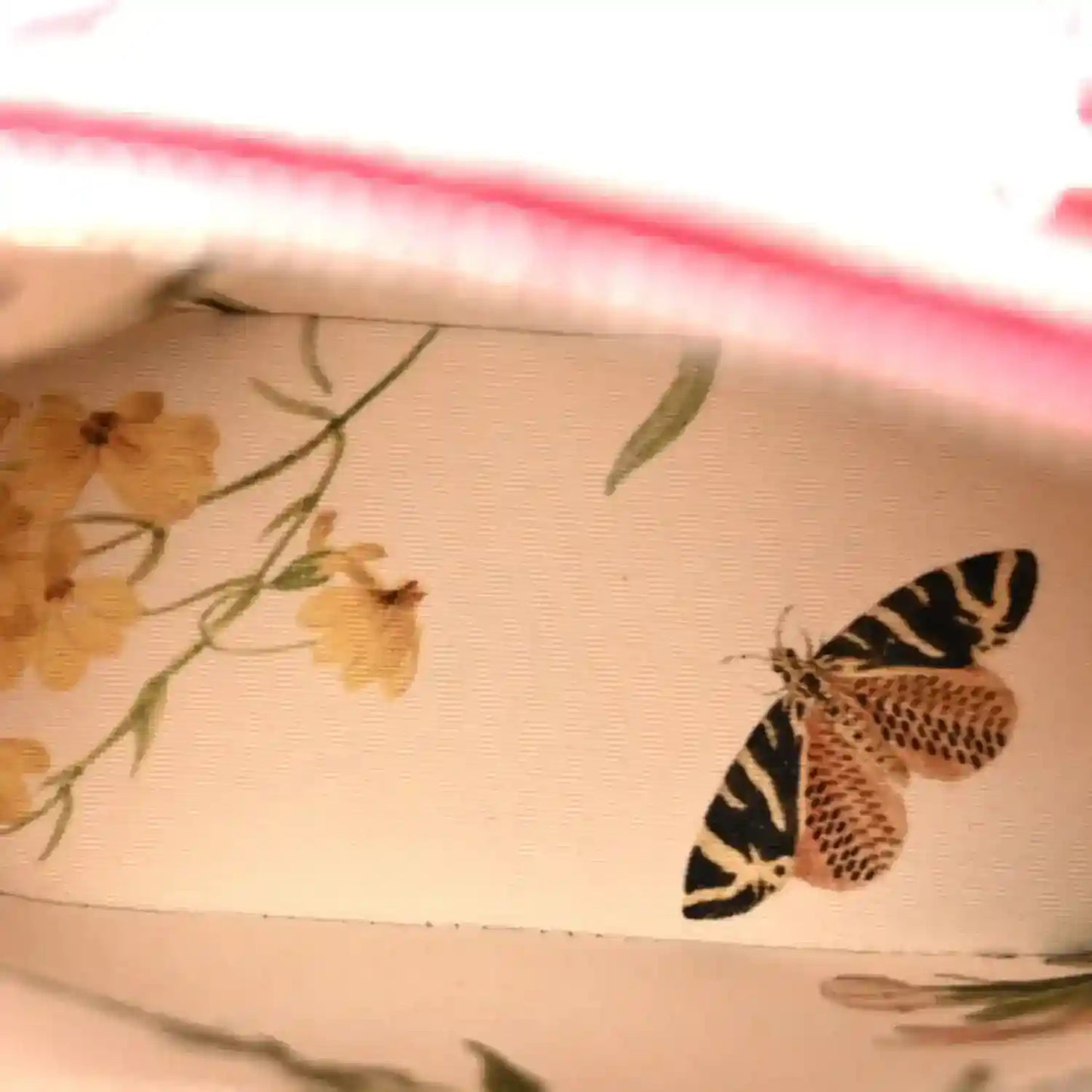 Printed fabric swatch with floral and butterfly motifs in beige and black