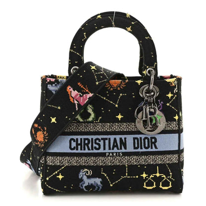 Medium black canvas handbag with embroidered zodiac motifs, top handles, and silver logo charms