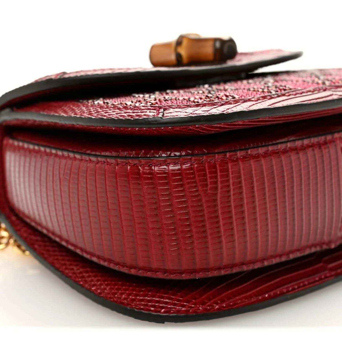 Red mini top-handle bag close-up of flap and textured edge binding beneath the clasp.