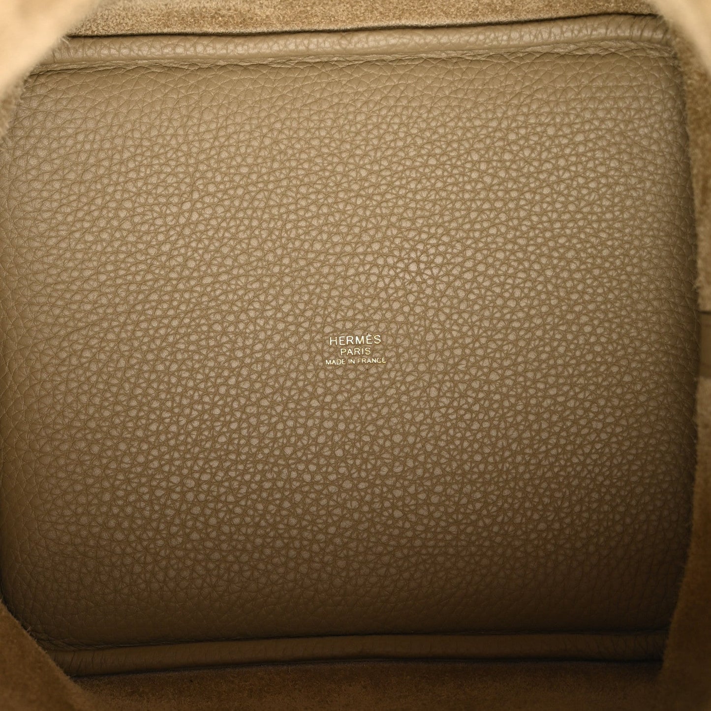Beige leather tote interior with embossed brand text and stitched trim