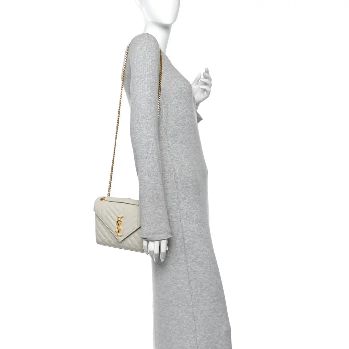 Cream quilted satchel on model, with gold chain shoulder strap and front monogram latch