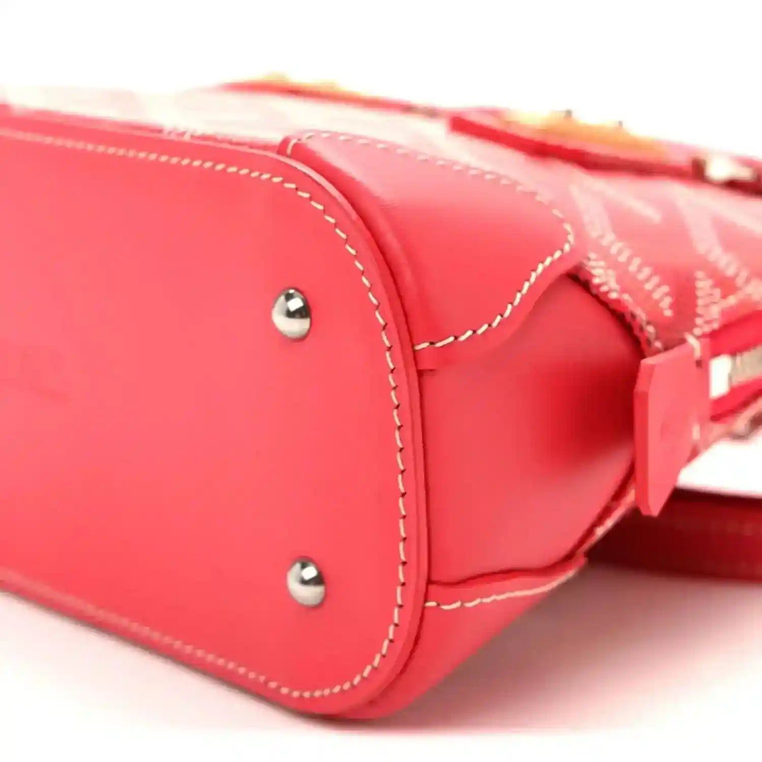 Red mini handbag close-up with silver studs, rounded base, and contrast stitching