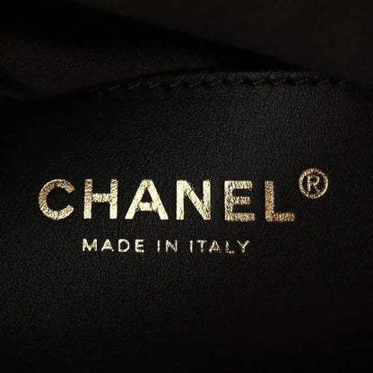 CHANEL logo and MADE IN ITALY on dark fabric with small circular mark