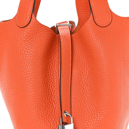 Orange leather handbag with top handle and metal clasp, side view