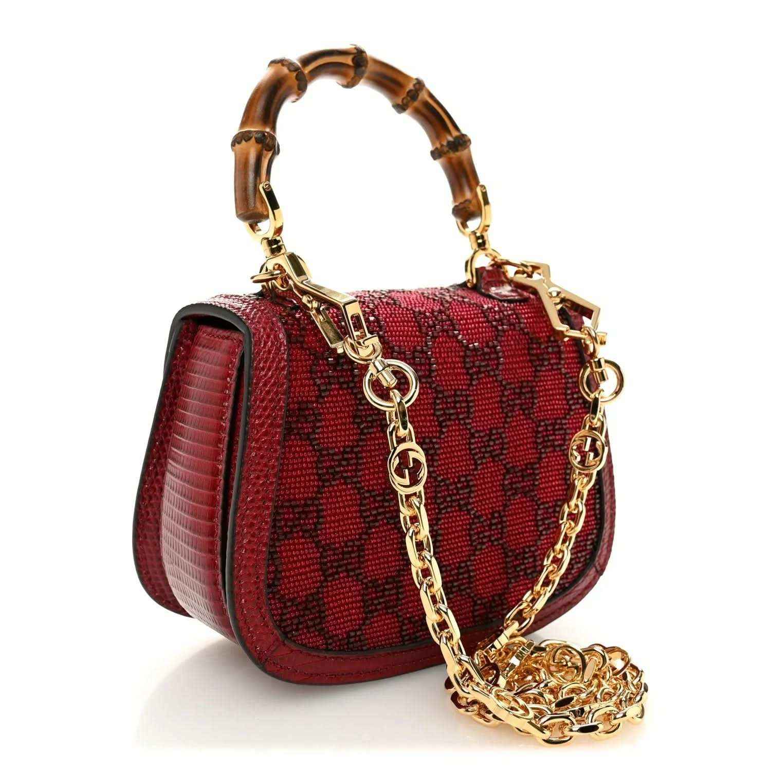 Red mini top-handle bag with textured pattern, gold chain strap, and front bar clasp hardware.
