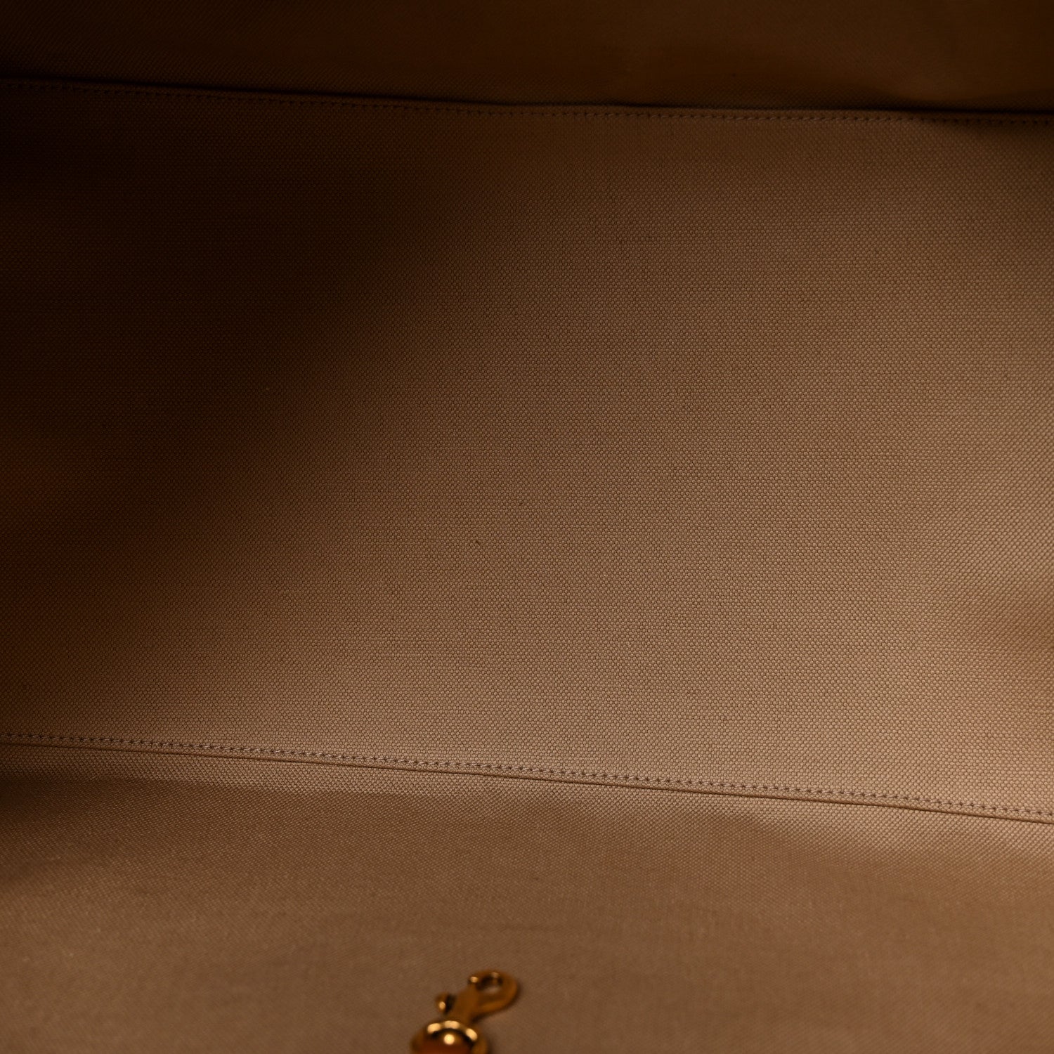 Close-up of tan canvas surface with brown leather edge and stitching