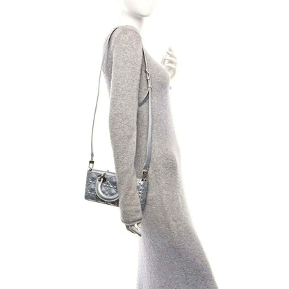 Small metallic silver handbag viewed from the side with shoulder strap and curved handle.