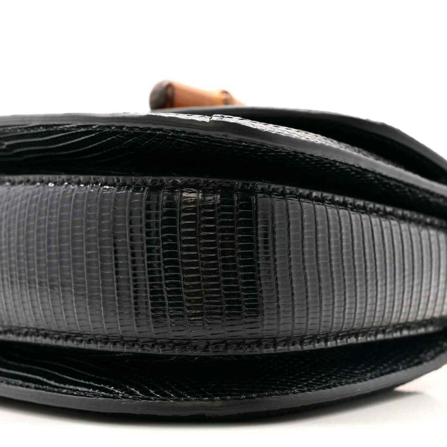 Close-up side of black mini bag exterior with textured panels and dark trim