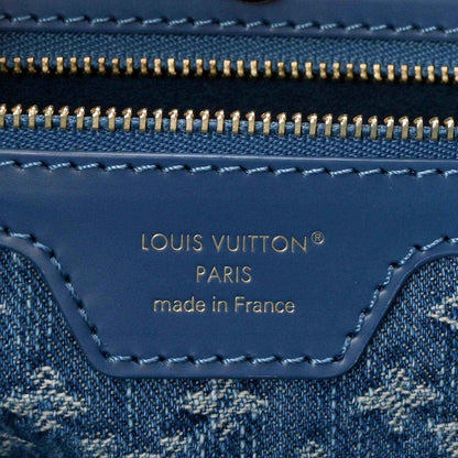 Denim blue leather tote bag close-up of logo label under gold zipper track