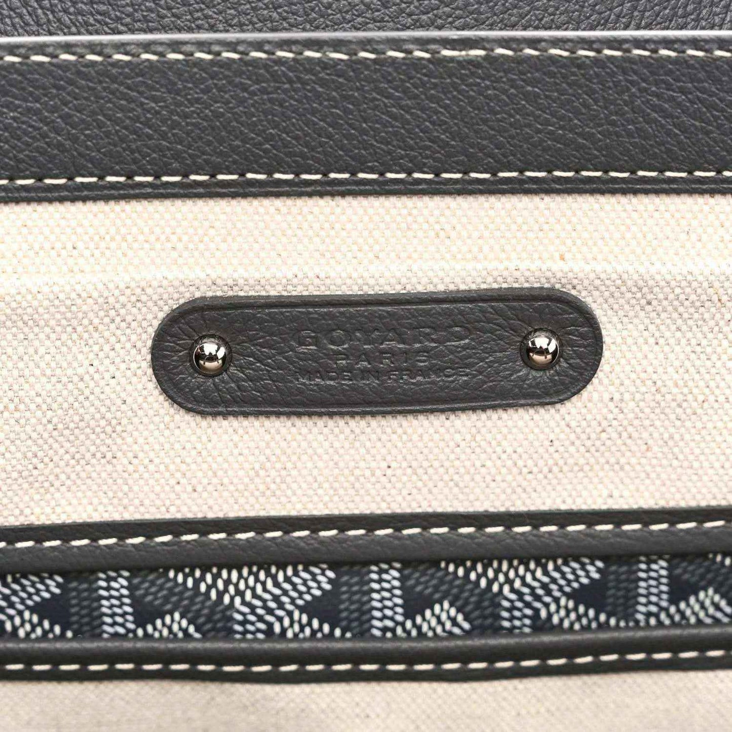 Leather tote pocket with embossed Goyardine mark and metal rivets, grey stitching