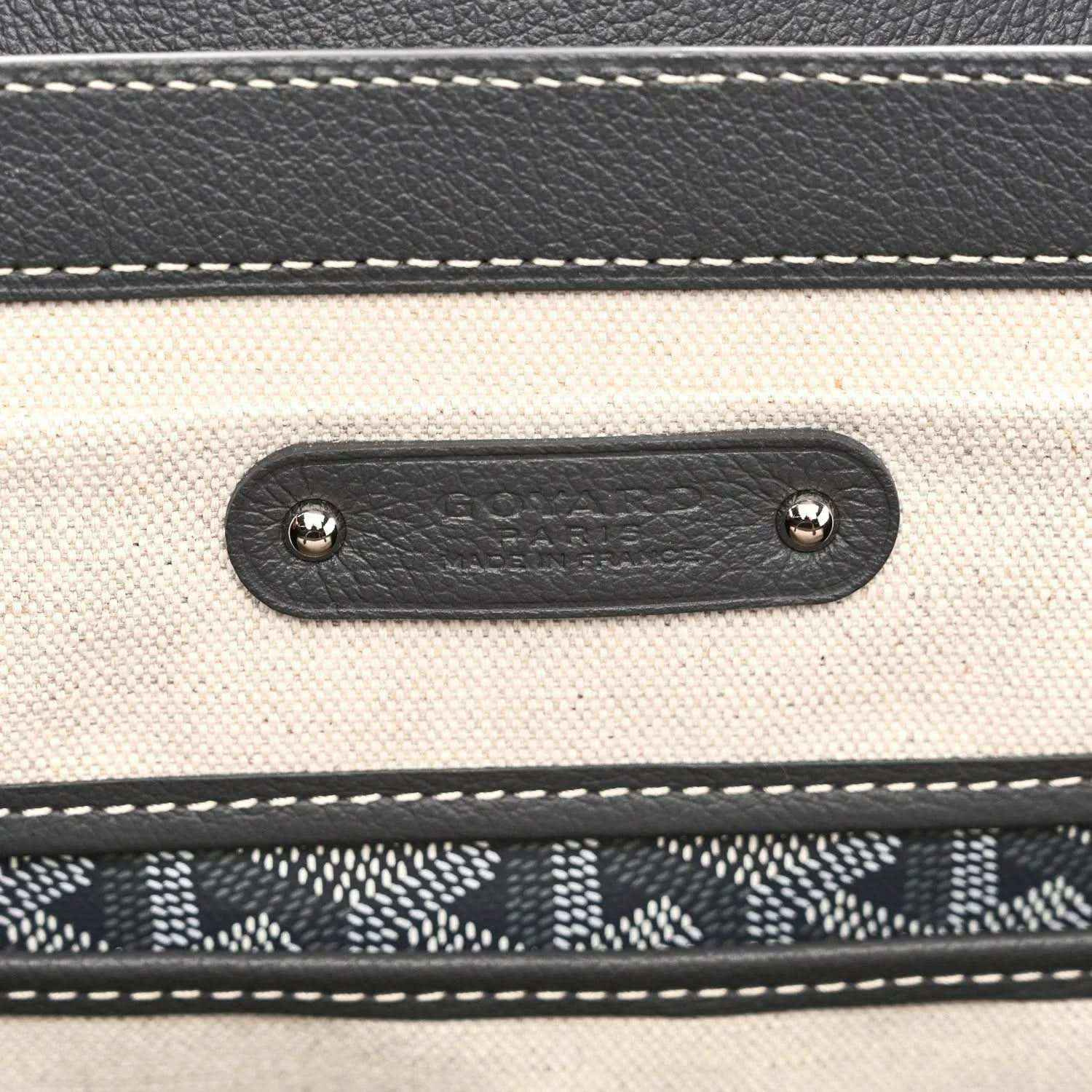 Leather tote pocket with embossed Goyardine mark and metal rivets, grey stitching