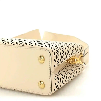 Louis Vuitton mini handbag close-up with two gold studs and patterned side panel