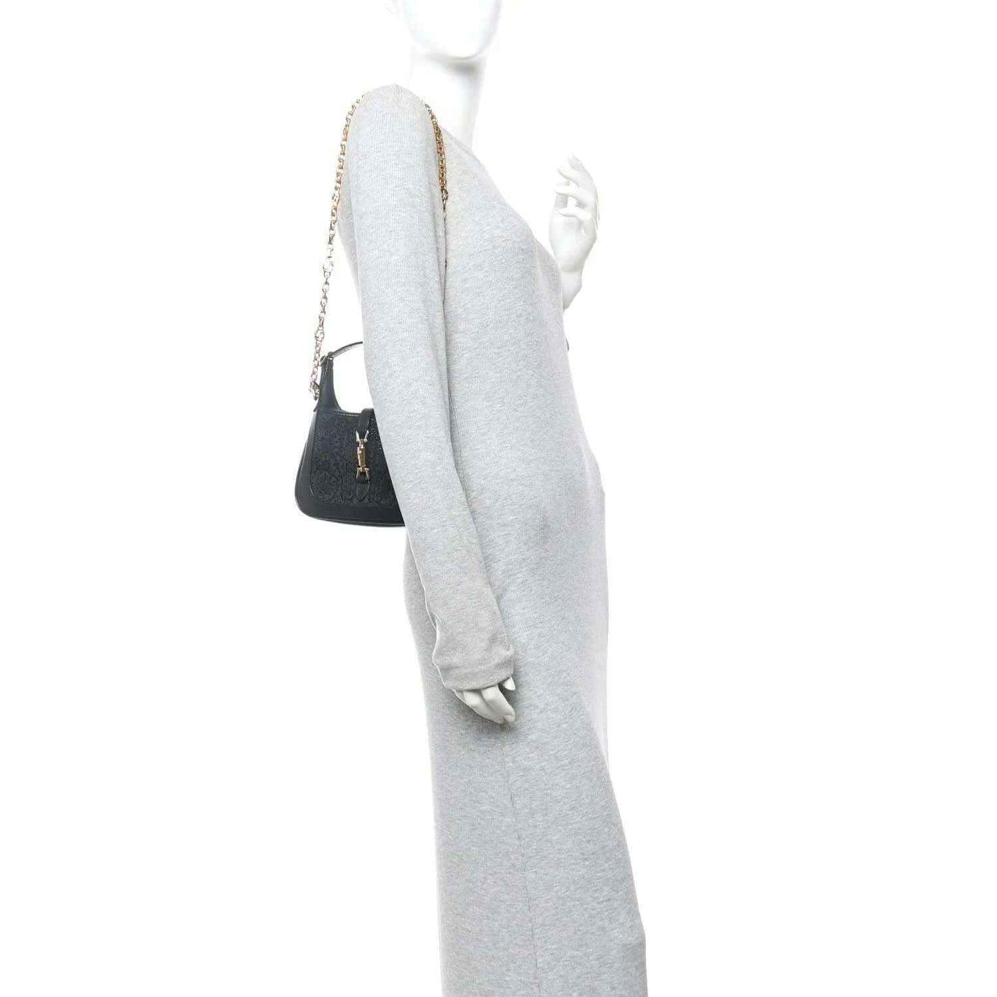 Black hobo bag worn on a model’s shoulder with a gold chain strap.