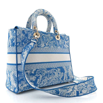 Blue embroidered handbag with top handles, gold hardware, and long strap attached.