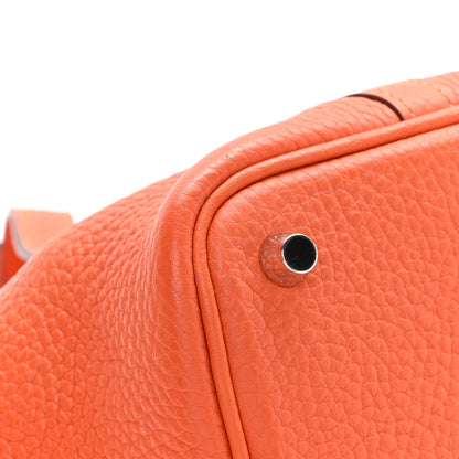 Orange pebbled leather handbag close-up of metal lock stud and grain texture