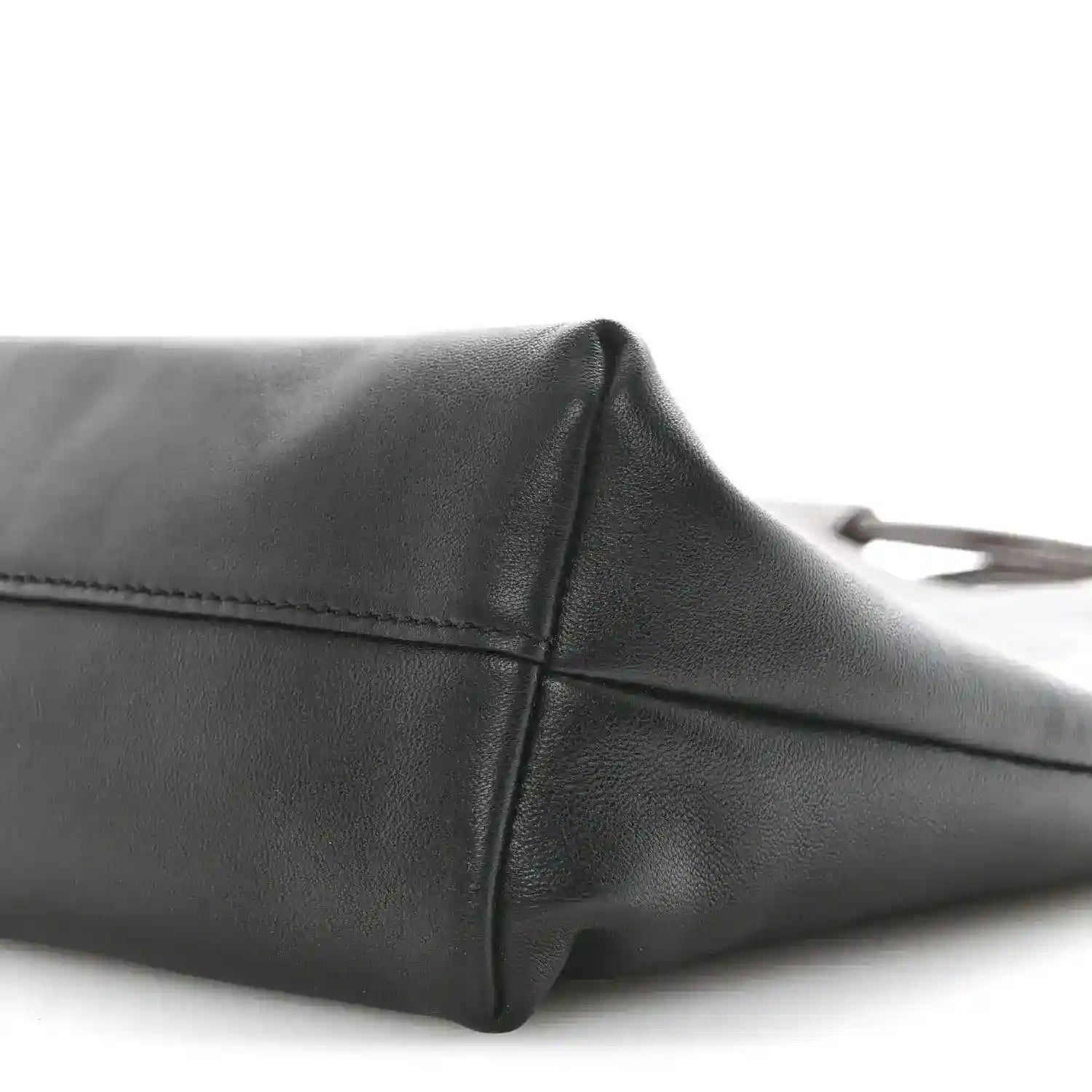 Black leather tote bag side panel with stitched edge and rounded corner.