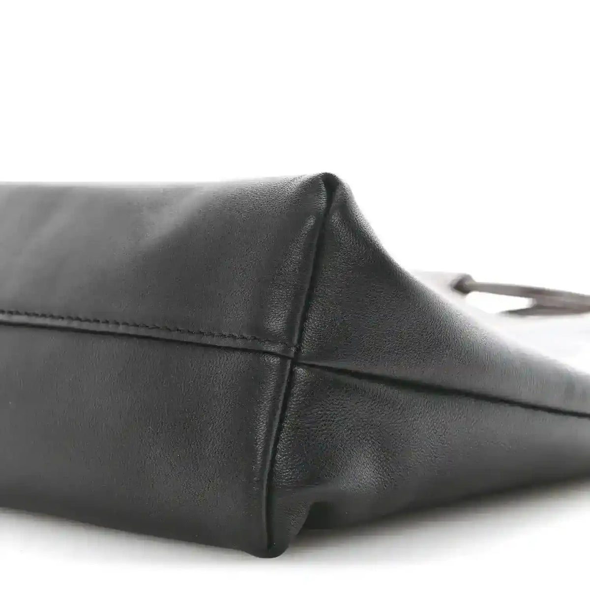 Black leather tote bag side panel with stitched edge and rounded corner.